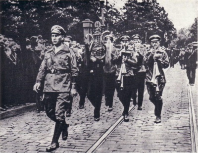 На фотографии из Федерального Архива Федеративной Республики Германия, помещенной нами в качестве иллюстрации к настоящей миниатюре, в ее заголовке, запечатлен председатель Коммунистической партии Германии (КПГ) - второй в мире по численности коммунистической партии, после советской Всесоюзной Коммунистической партии (большевиков) -, депутат германского парламента-рейхстага от КПГ Эрнст Тельман во главе колонны боевиков Союза Красных Фронтовиков (Ротфронта). Непосредственно за Эрнстом Тельманом в колонне марширует оркестр гобоистов-шальмейщиков.